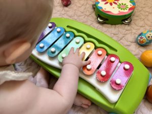 a baby plays with a toy xylophone