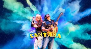 a singer and guitarist stand in an explosion of colour