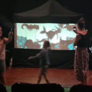 children and a parent walk in front of a shadow puppet tent