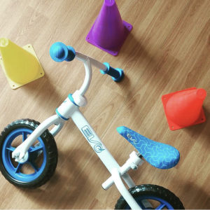 a balance bike is on the ground with brightly coloured cones