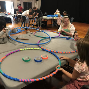 children wrap brightly coloured tape around hula hoops