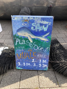 a hand drawn sign for the show with a picture of a whales reads "Plastic Ocean FREE" with the times of the shows